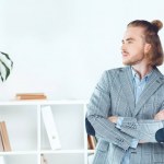 Handsome businessman standing in office with crossed arms and looking away