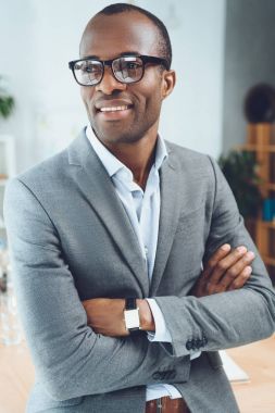 smiling african man with arms crossed looking away at office space  clipart