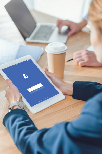 обрезанное изображение женщины, держащей цифровой планшет во время сидения за столом
 