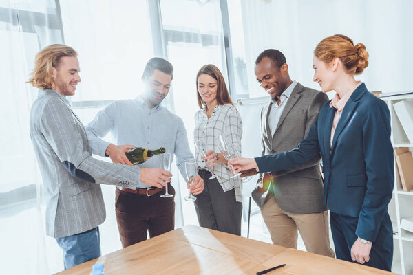 Человек в рубашке наливает шампанское в бокалы
 