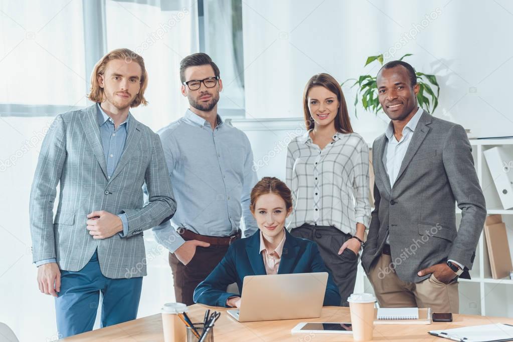 business team standing against sitting woman at office space  