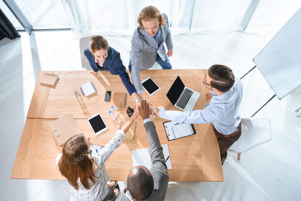business team shaking hands over table at office space  