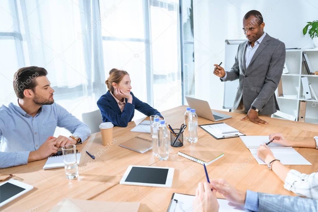 african man standing against laptop on table at office space 