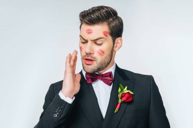 portrait of handsome groom in suit with red lipstick on face clipart