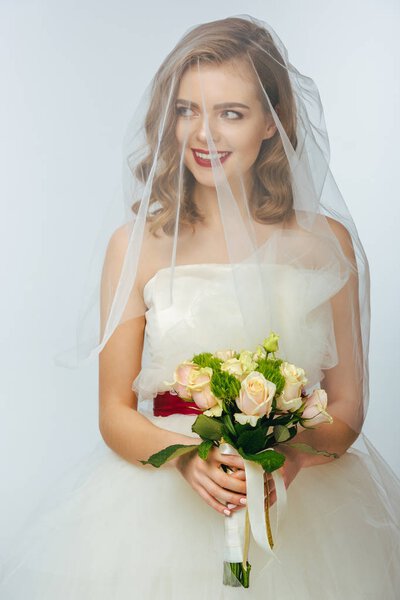 portrait of pretty bride in wedding dress and veil with wedding bouquet in hands