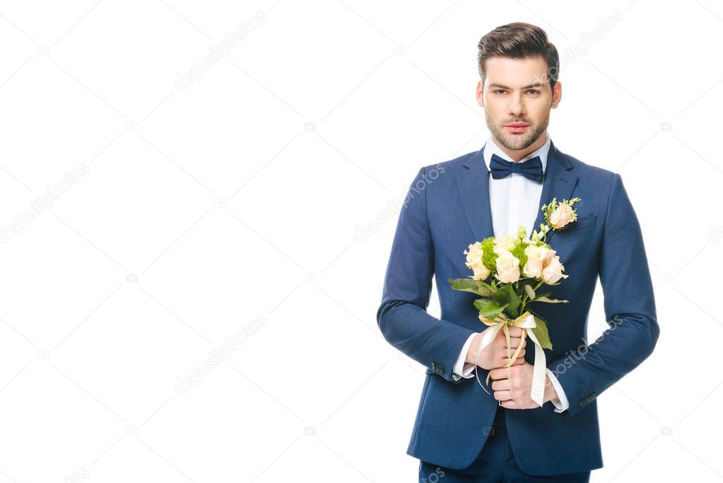 portrait of stylish groom in suit with wedding bouquet isolated on white