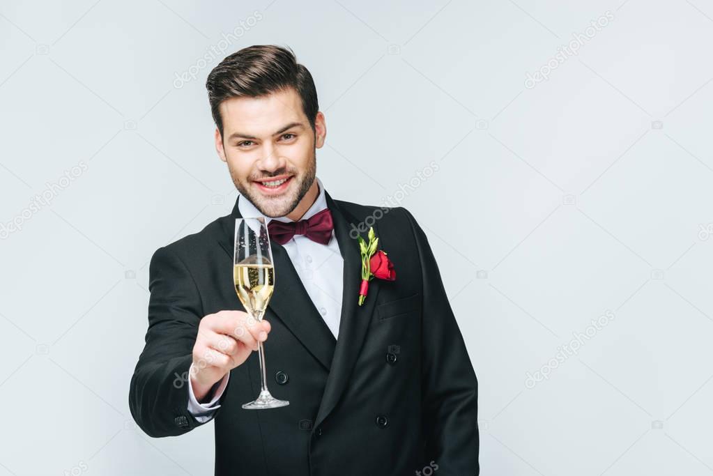 portrait of smiling man with glass of champagne isolated on grey