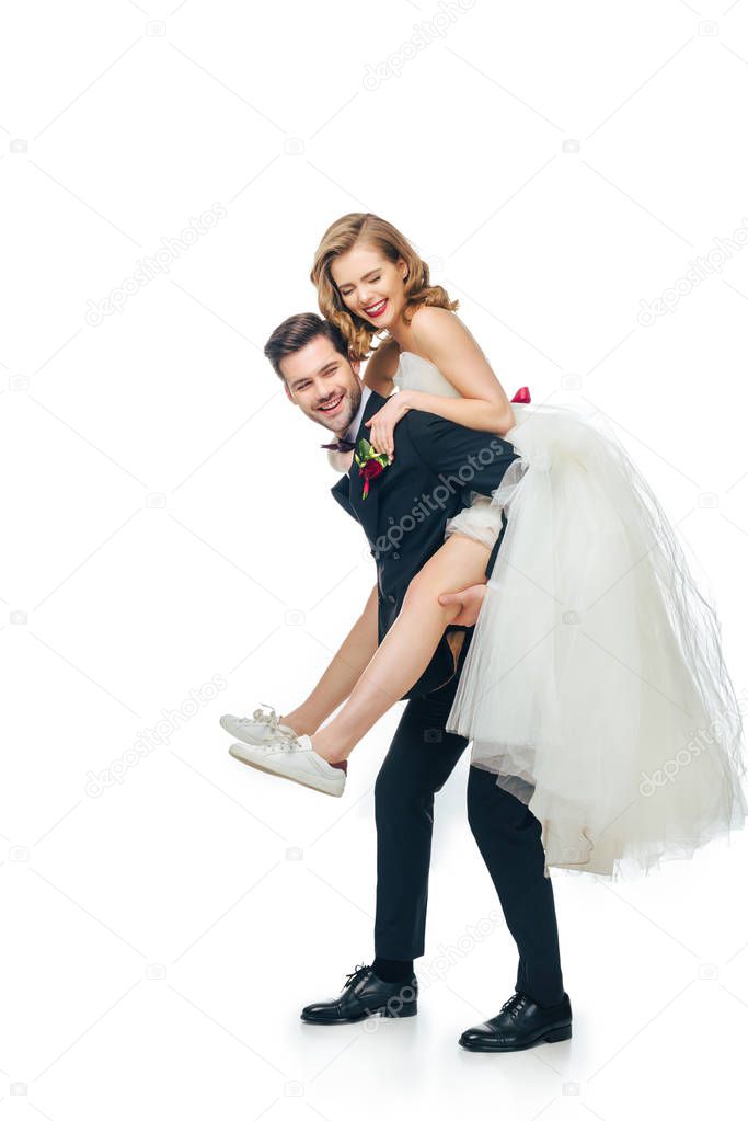 side view of groom and bride piggybacking together isolated on white