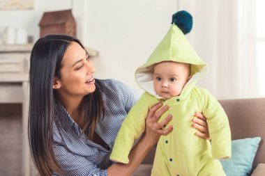 elinde evde küçük bebek bakarak gülümseyen kadın portresi