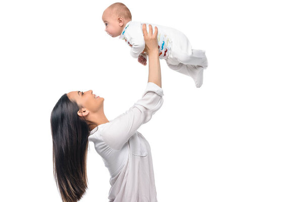 side view of cheerful woman holding infant baby isolated on white