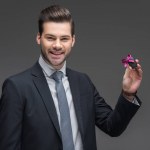 Smiling businessman holding car key, isolated on grey