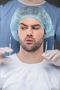 bearded handsome man in medical cap choosing beauty injections, isolated on grey clipart