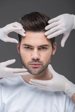 handsome man and doctors hands, isolated on grey, skin care concept clipart