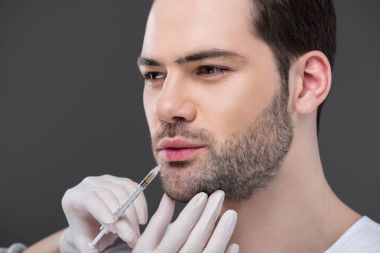 hands in medical gloves making beauty injection for bearded man, isolated on grey clipart