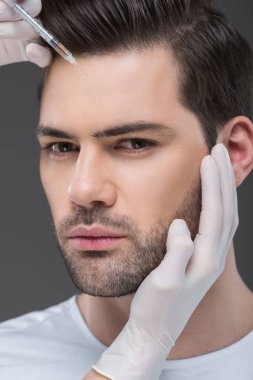 yakışıklı adam, gri izole için güzellik enjeksiyon yapma Medikal Ürünler ellerinde