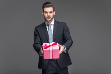Mevcut, tutan takım elbiseli yakışıklı adam gri izole
