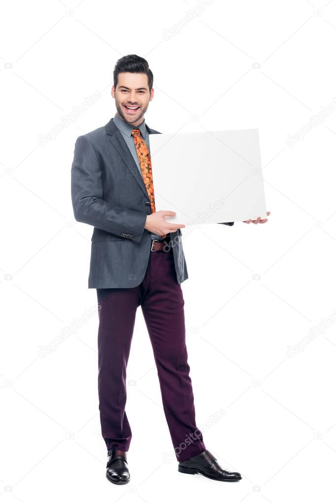 smiling businessman in suit holding blank placard, isolated on white
