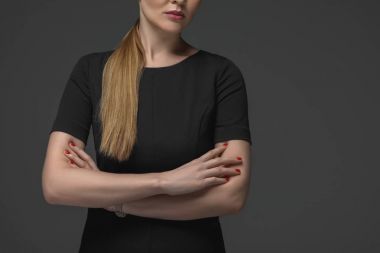 kırpılan siyah elbise ayakta çapraz kolları üzerinde gri izole olan kadında doz