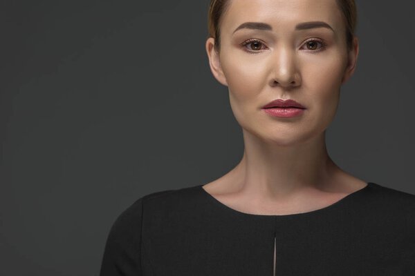 portrait of beautiful kazakh woman looking at camera isolated on grey 