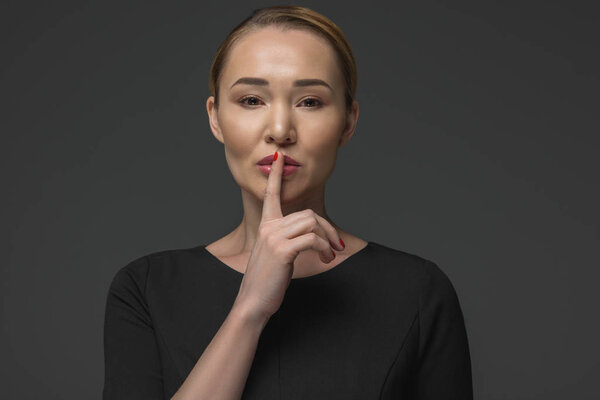 beautiful kazakh woman gesturing for silence isolated on grey