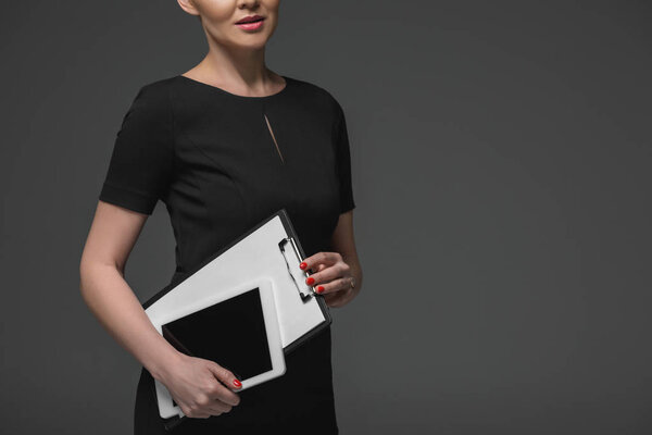 cropped shot of kazakh businesswoman holding digital tablet and clipboard isolated on grey