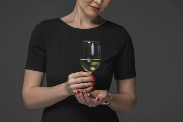 cropped shot of woman in black dress holding glass of wine isolated on grey 