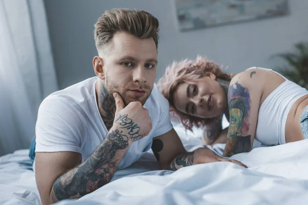 Hermosa Pareja Tatuada Mirando Cámara Mientras Relaja Cama — Foto de Stock