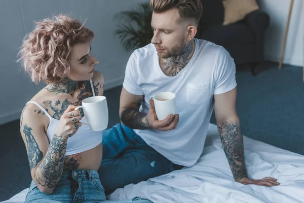 Giovane Coppia Tatuata Guardando Altro Bevendo Caffè Letto Mattino — Foto Stock