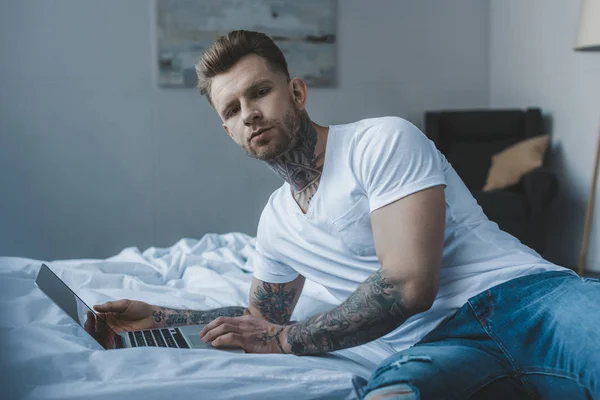 Hombre Tatuado Guapo Mirando Cámara Mientras Usa Ordenador Portátil Cama — Foto de Stock