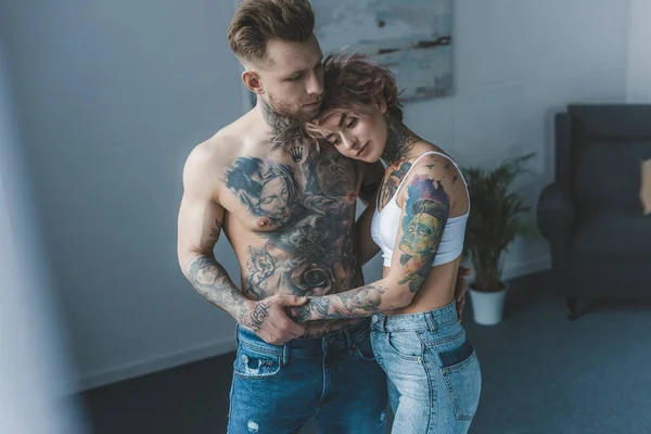 Νέοι Τατουάζ Κομψό Ζευγάρι Αγκάλιασμα Στο Υπνοδωμάτιο — Φωτογραφία Αρχείου