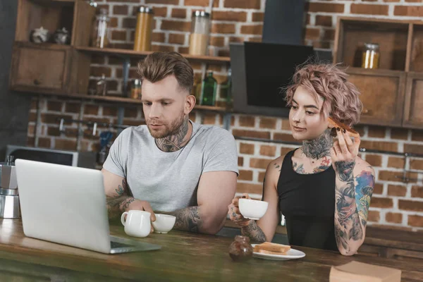 Tattooed Couple Using Laptop Eating Toasts Breakfast Kitchen — Stock Photo, Image
