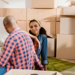 Pareja afroamericana soñadora en apartamento nuevo con cajas de cartón