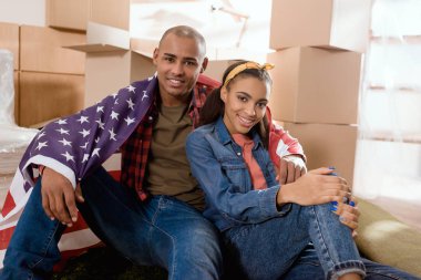Afrika kökenli Amerikalı çift kat karton kutular ile yeni evde oturan Amerika Birleşik Devletleri bayrağı ile