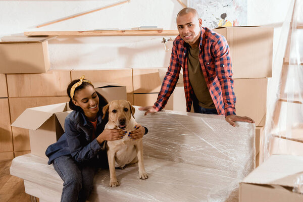 african american couple with labrador dog and cardboard boxes at home