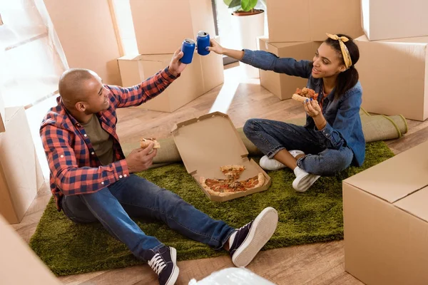 Pareja Afroamericana Comiendo Pizza Tintineo Con Latas Refresco Nuevo Apartamento —  Fotos de Stock