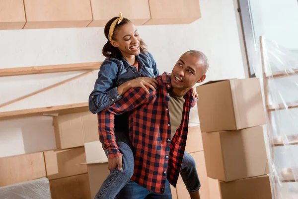 Feliz Casal Afro Americano Piggybacking Novo Apartamento Com Caixas Papelão — Fotografia de Stock