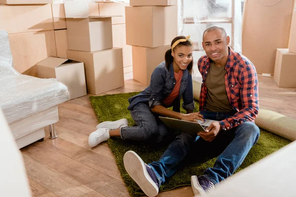 Pareja Afroamericana Usando Portátil Nuevo Apartamento Con Cajas Cartón —  Fotos de Stock