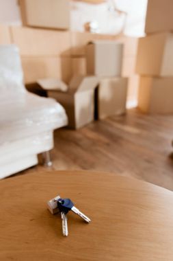 keys on table in new apartment with cardboard boxes, moving concept clipart