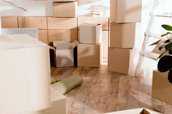 rolled carpet and cardboard boxes in new apartment, moving concept