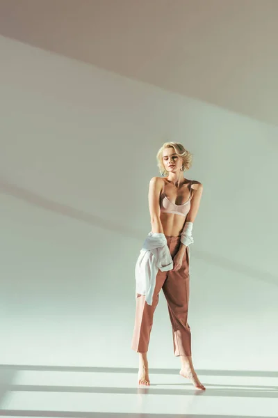 Barfüßiges Blondes Mädchen Rosa Hemd Und Hose Posiert Auf Grau — Stockfoto