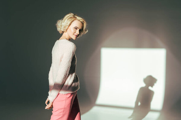 beautiful blonde girl smiling at camera while posing in studio