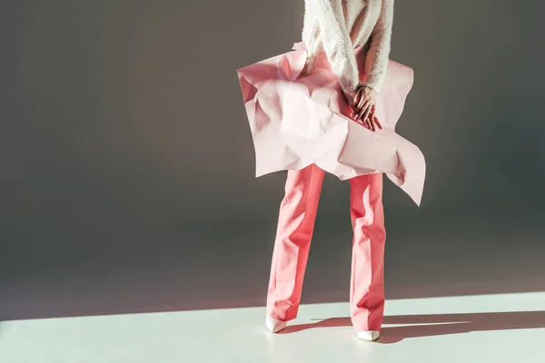 スタイリッシュな女の子がスタジオで腰にピンクの紙を丸めてポーズのショットをトリミング  — 無料ストックフォト