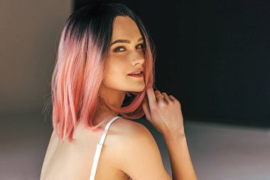 Güzel gülümseyen kız pembe saçlı moda çekimi için poz veren