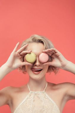 Dudak yalama ve iki macarons izole kırmızı göz önünde tutan güzel kız