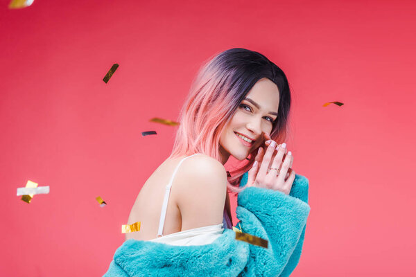 happy beautiful girl posing in blue fur coat, isolated on pink with confetti