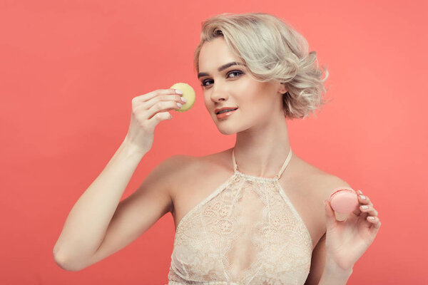 beautiful blonde woman with two delicious macarons, isolated on red
