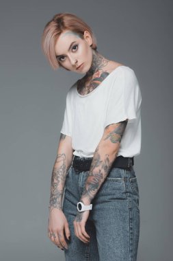 Beyaz t-shirt giyen ve gri izole kamera bakarak dövmeli güzel kız portresi