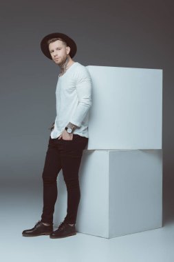 cepler ve kameraya gri görünümlü şık dövmeli delikanlı ile şapka ayakta eller