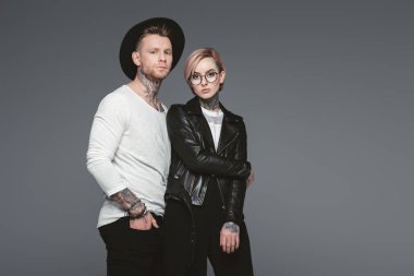 stylish tattooed couple posing together, isolated on grey  clipart