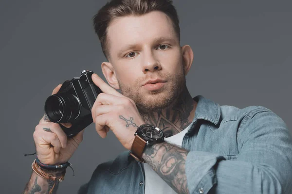 Joven Guapo Con Tatuajes Sosteniendo Cámara Mirando Cámara Aislada Gris — Foto de Stock